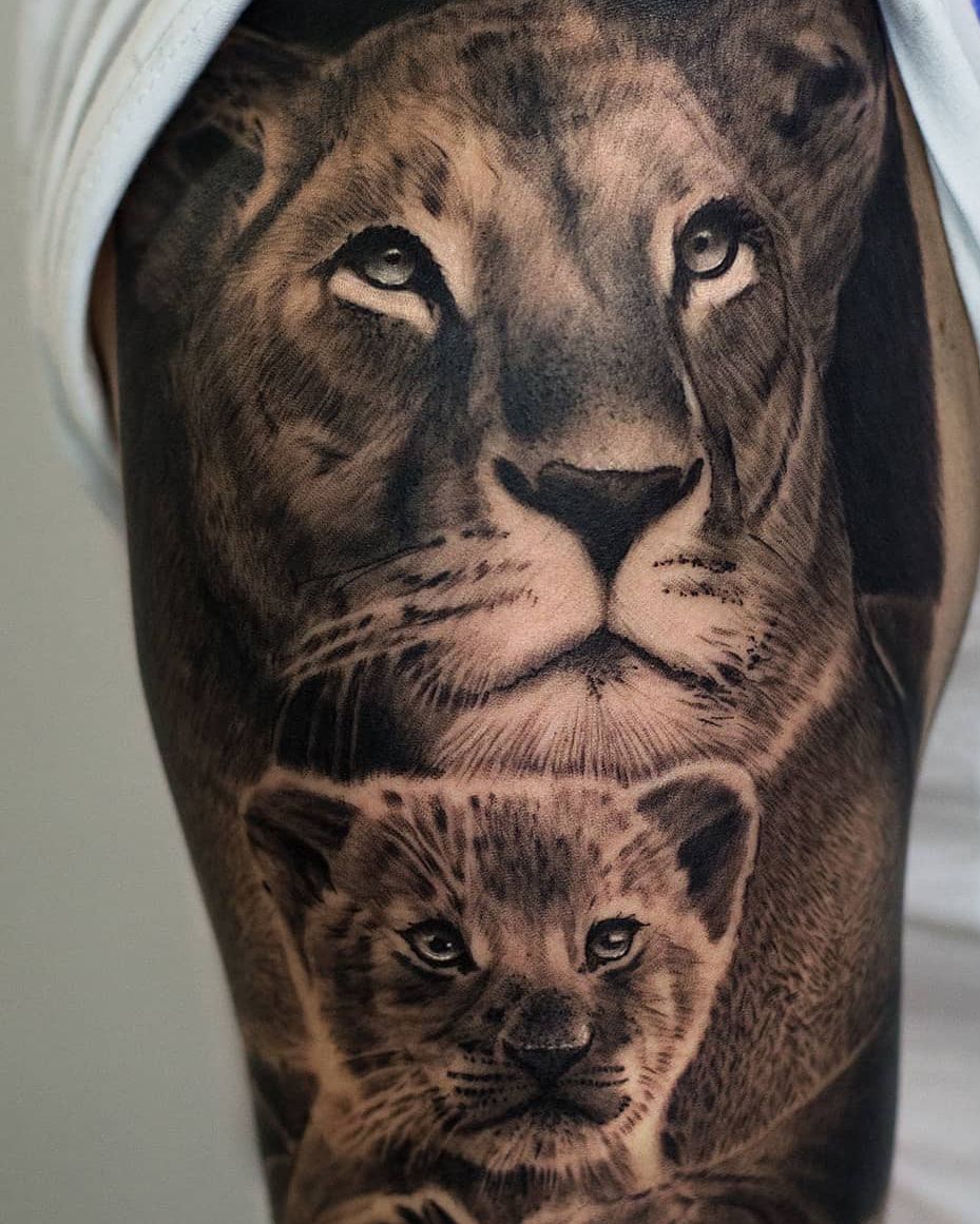 Lionne veillant sur son lionceau, regards lumineux, réalisme noir et gris fraîchement tatoué sur le haut du bras