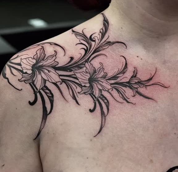 Ornement floral sombre de lys et de volutes effilées, de l’épaule jusqu’à la clavicule