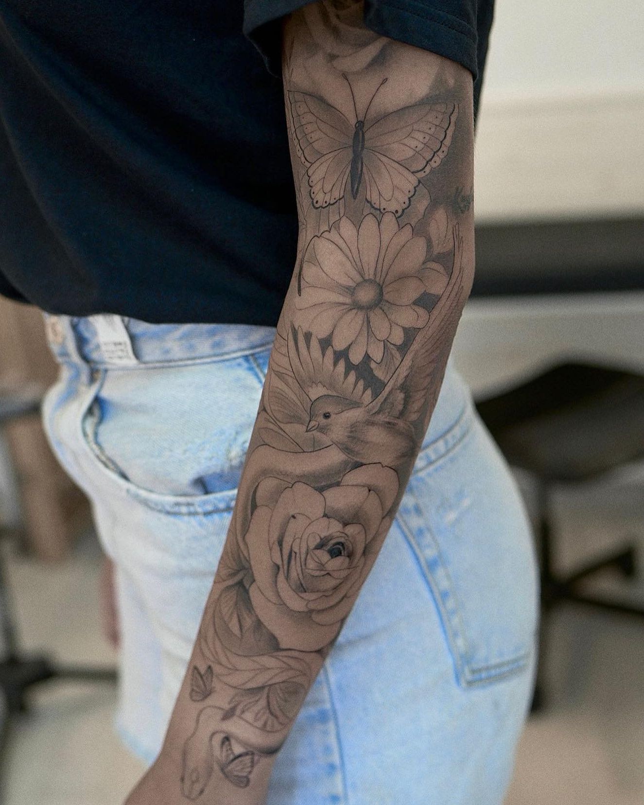 Manga en negro y gris: mariposa, margarita, pájaro en vuelo, rosa y hojas con sombreado suave hasta la muñeca