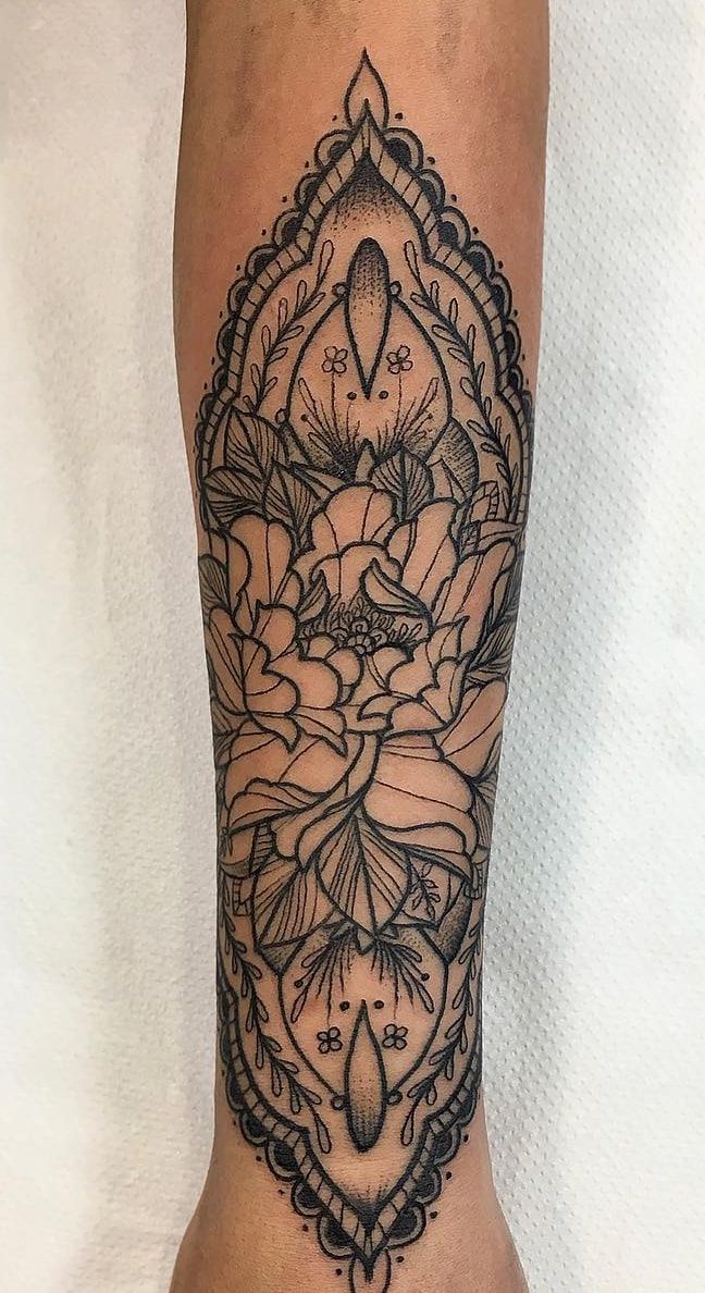 Pivoine au trait encadrée d’un mandala symétrique en dentelle et en pointillé, sur toute la longueur de l’avant-bras