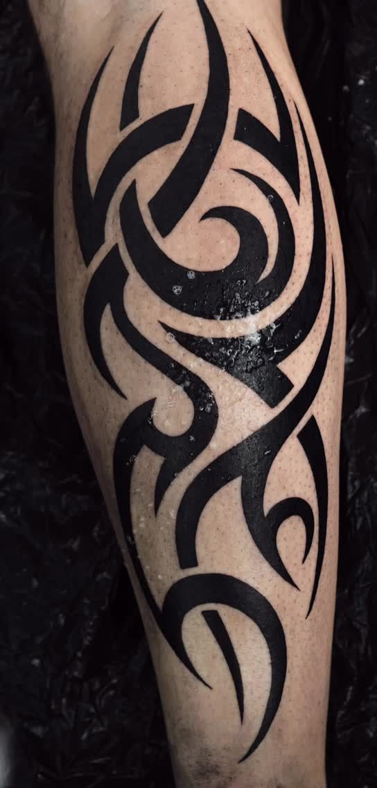 Tribal aux formes courbes et pointues en aplats de noir sur toute la longueur du mollet
