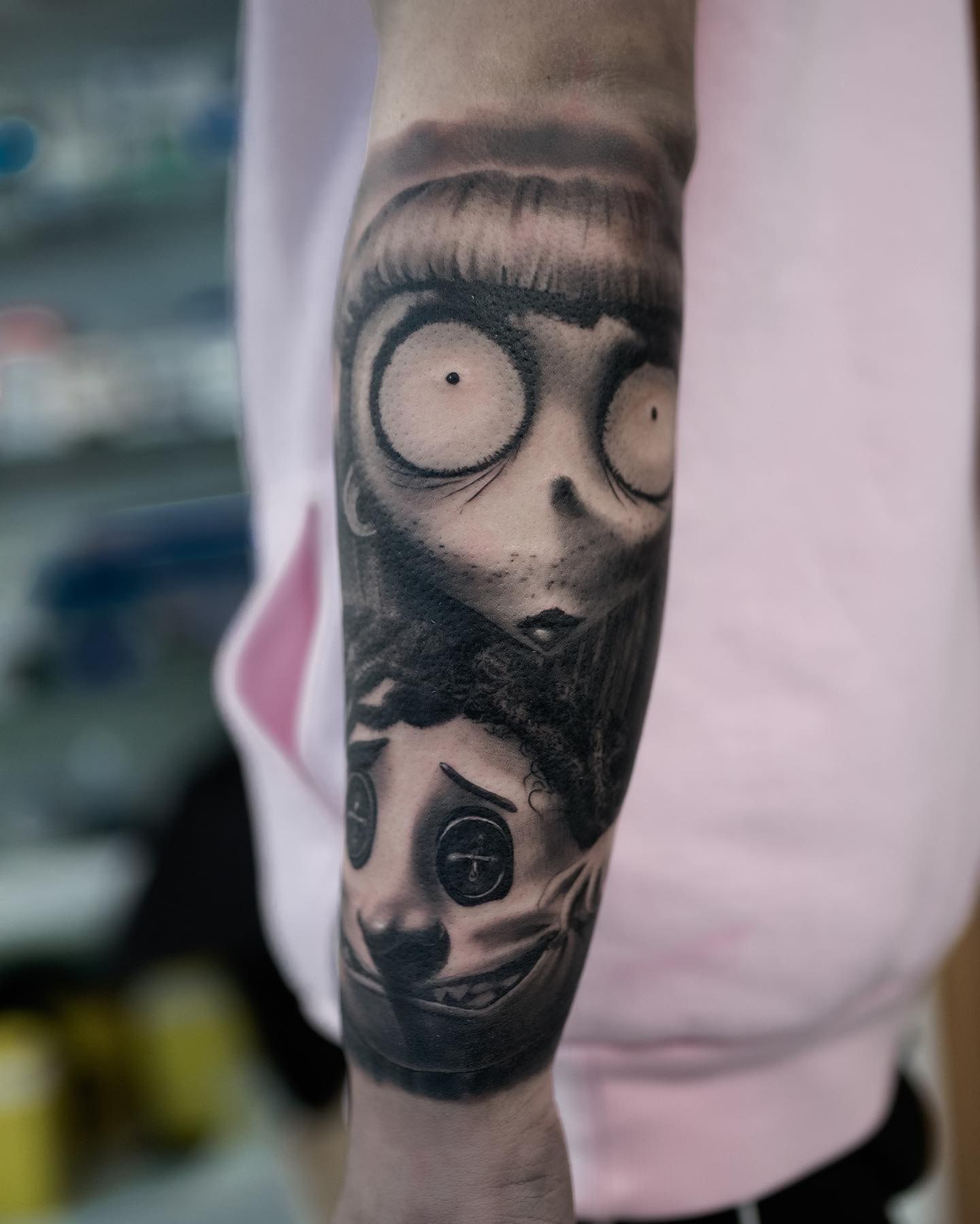 Fillette aux yeux immenses et poupée aux yeux-boutons, réalisme noir et gris contrasté, cicatrisé, sur l’avant-bras
